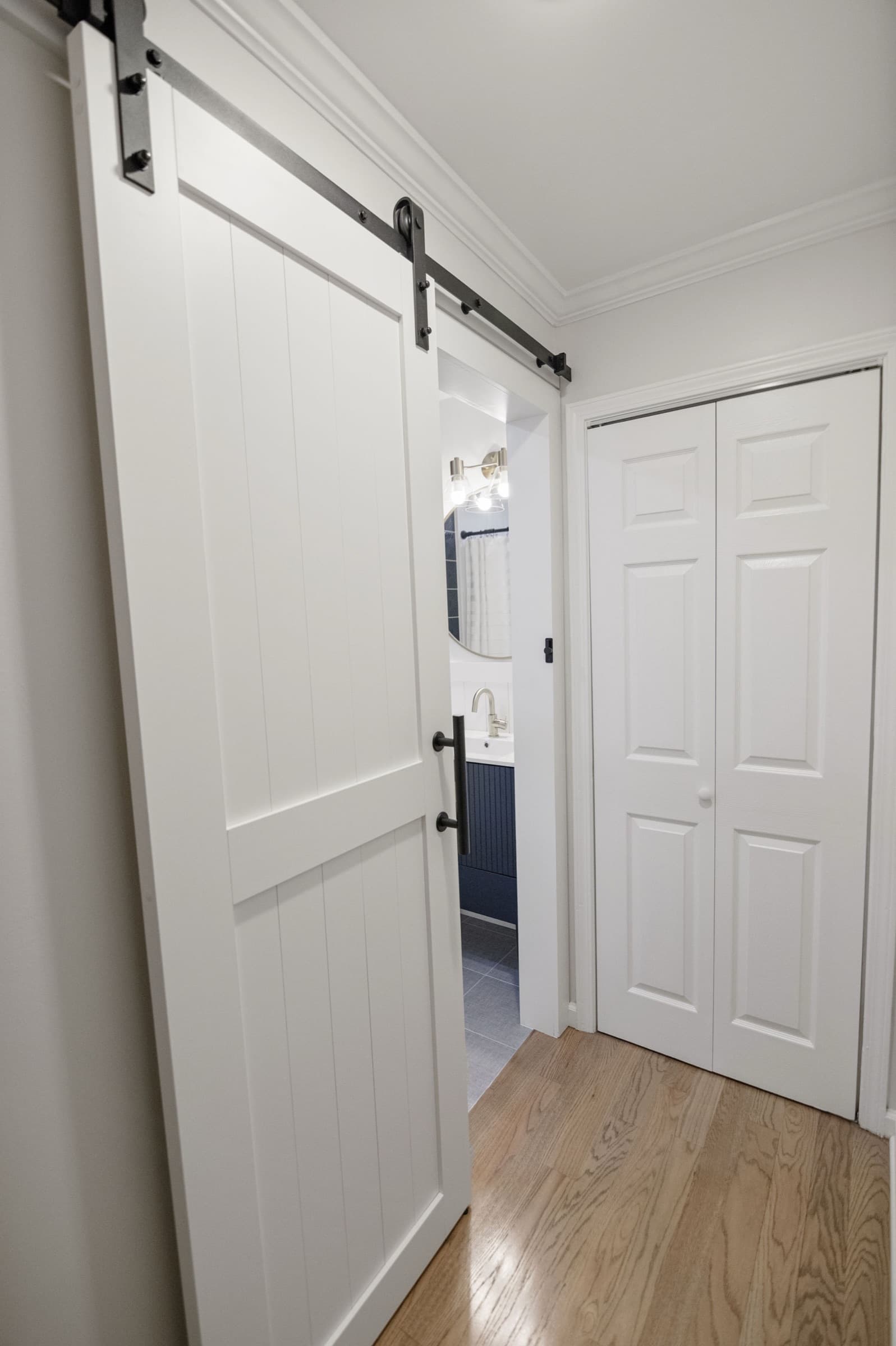 Candlestick Ct renovation — hallway view through sliding barn door into the hall bathroom