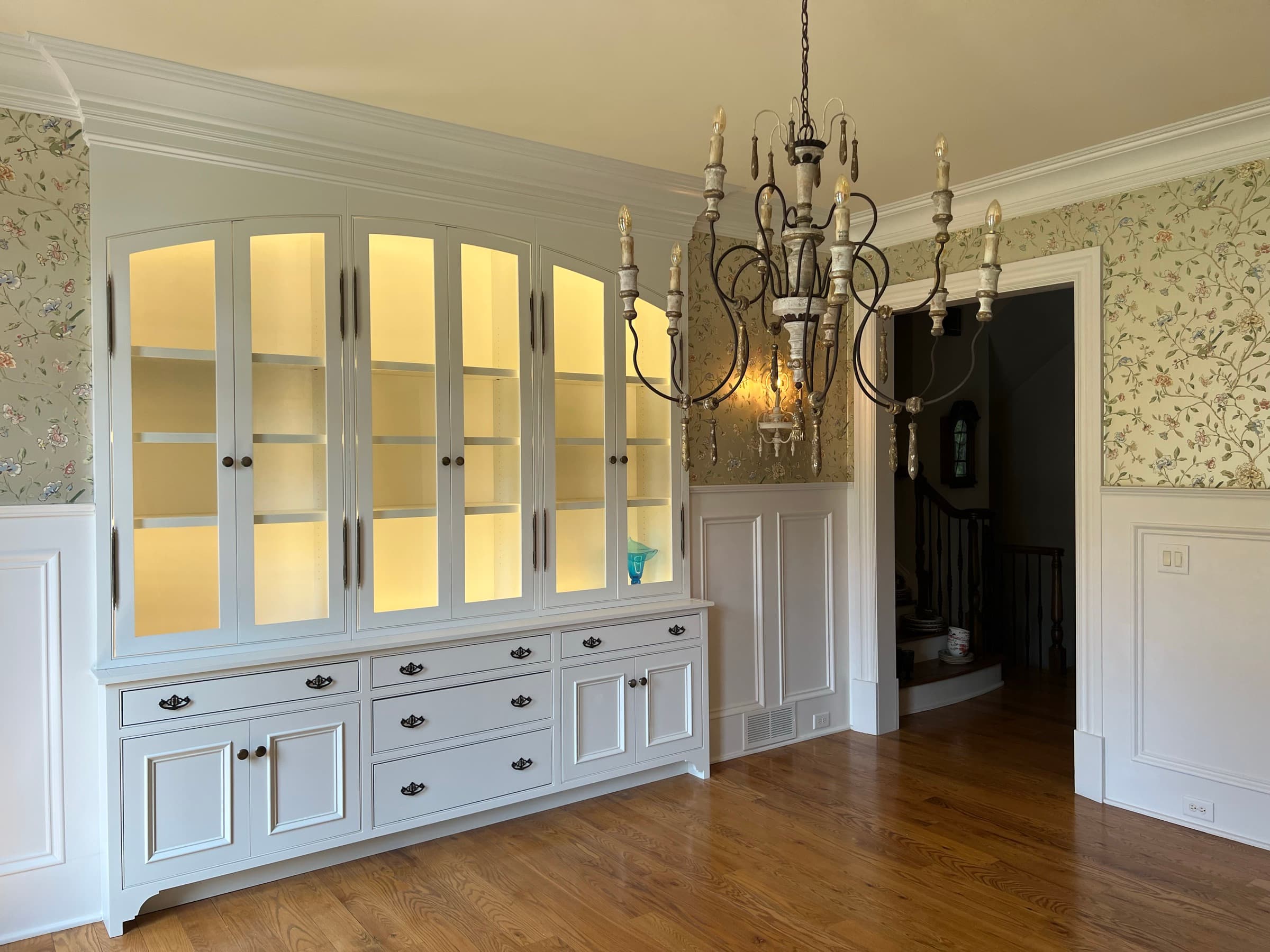 Custom dining room china cabinet — angled view with chandelier and hardwood floors