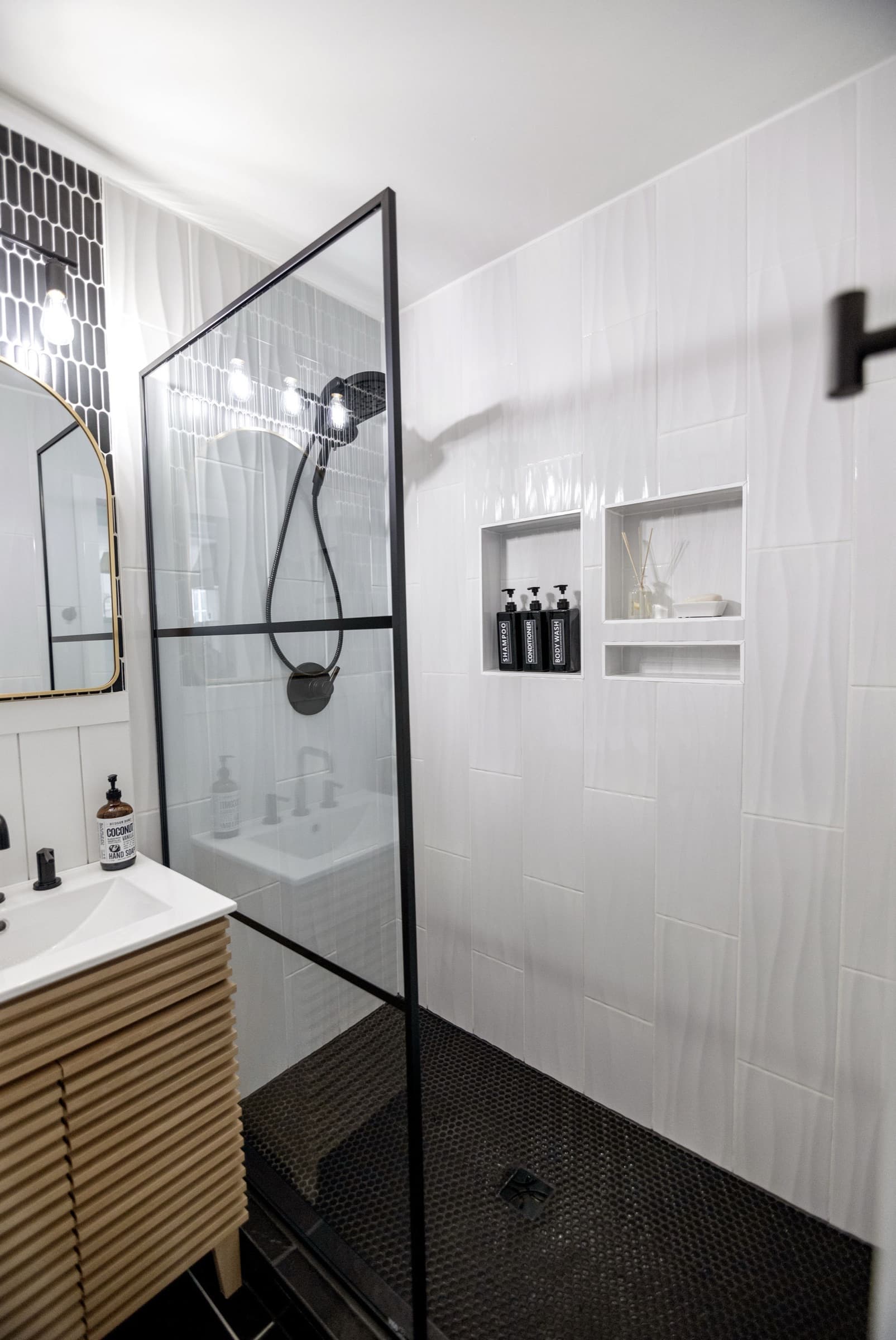 Candlestick Ct downstairs bathroom — glass walk-in shower with black penny tile floor and tiled niches