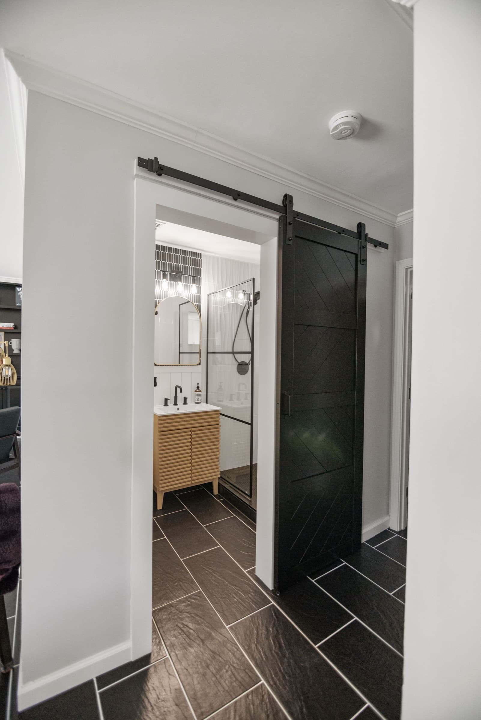 Candlestick Ct renovation — hallway view through black barn door into the downstairs bathroom
