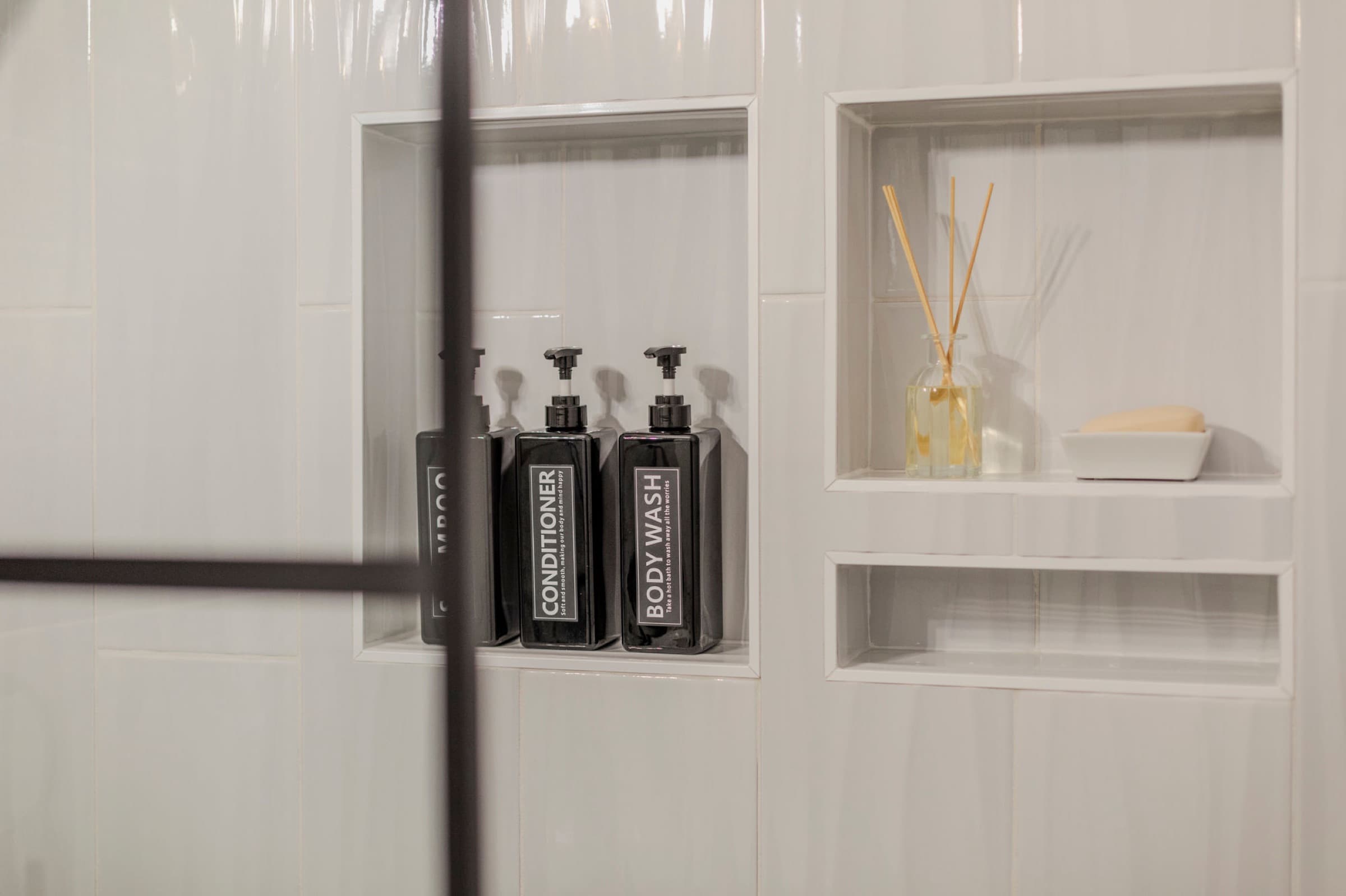 Candlestick Ct downstairs bathroom — tiled shower niche with styled bottles and diffuser