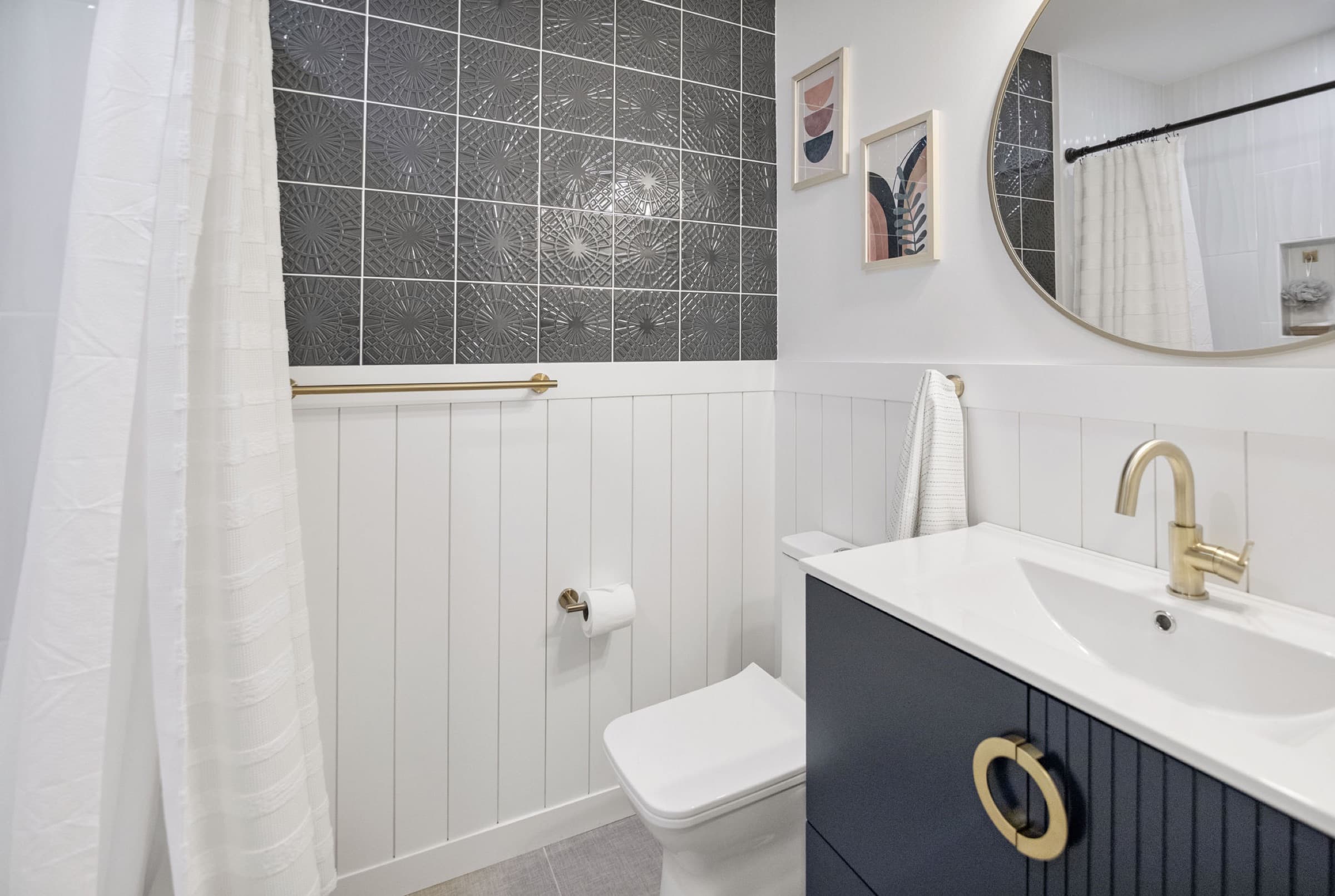 Candlestick Ct hall bathroom — toilet and navy vanity with round mirror
