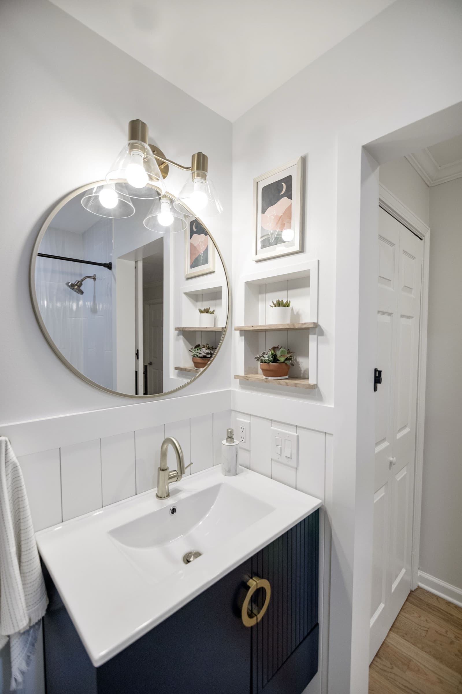 Candlestick Ct hall bathroom — round brass-framed mirror and gold vanity sconce