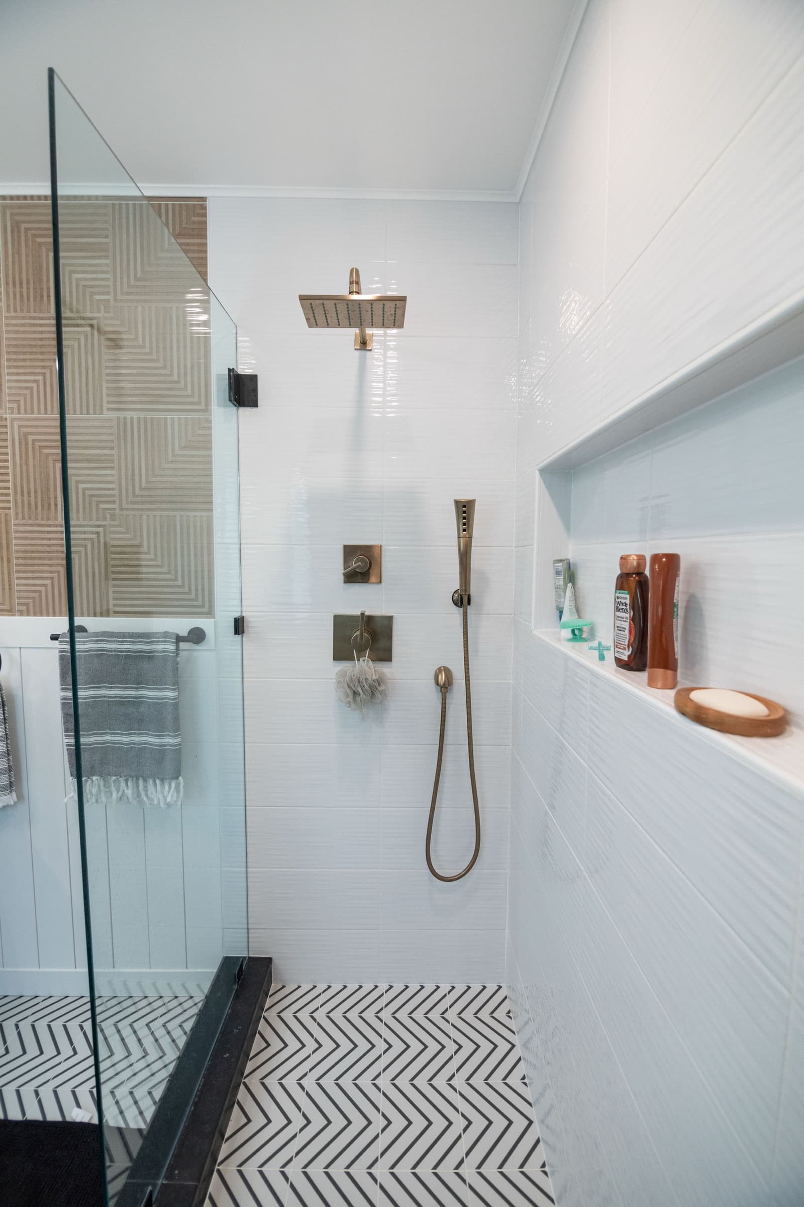 Candlestick Ct primary bathroom — glass walk-in shower with brass fixtures and chevron floor tile