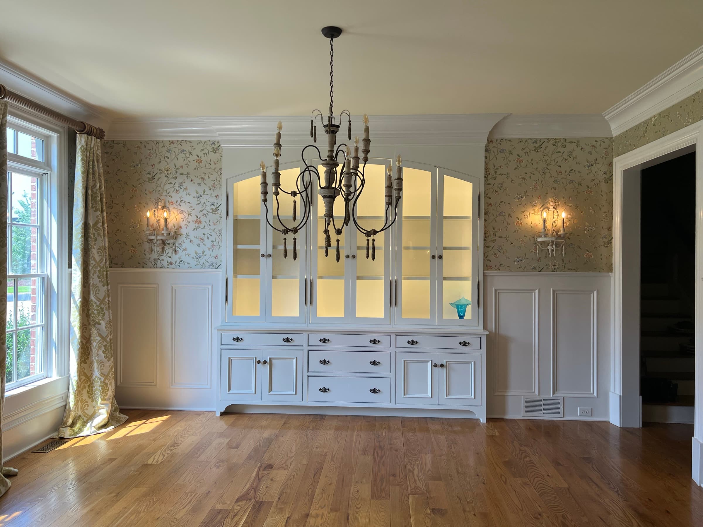 Custom dining room china cabinet — built-in cabinetry against wainscoting and floral wallpaper