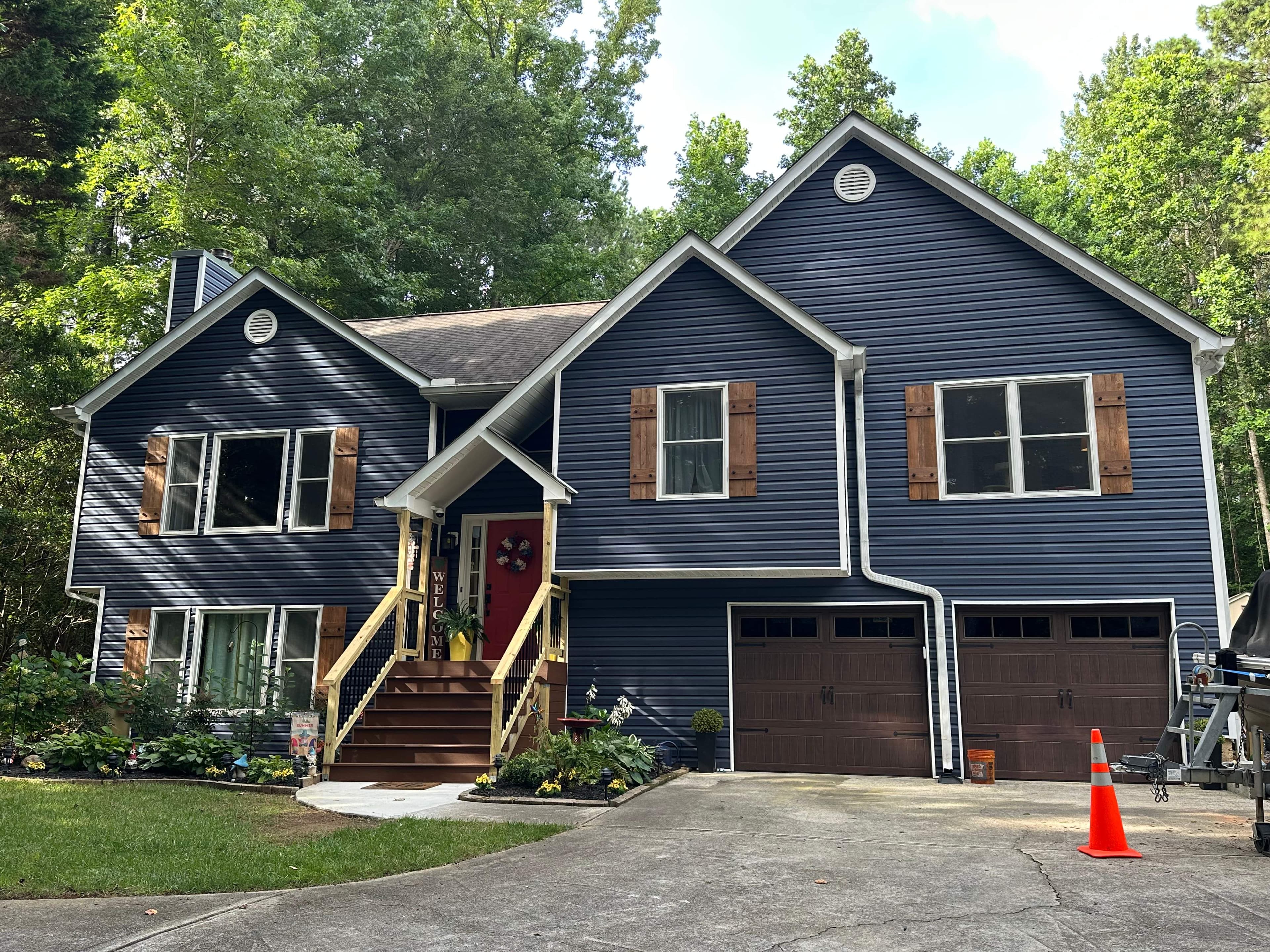 Maddox Rd exterior renovation — new Marine Blue siding, cedar-style shutters, and carriage-style garage doors